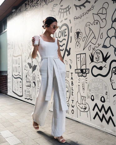 woman holding cup walking beside wall