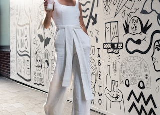 woman holding cup walking beside wall