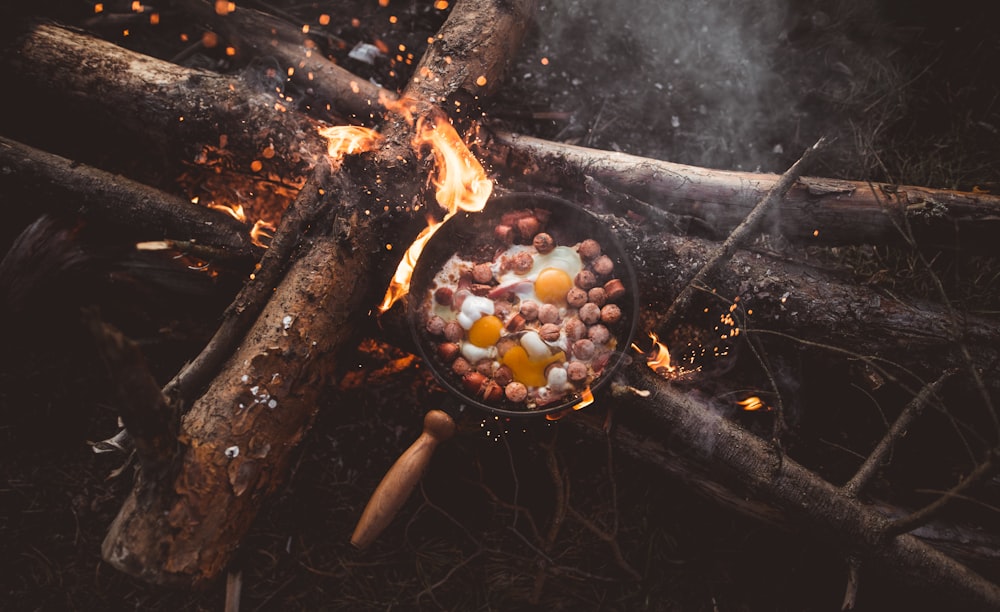 frying pan with food on lit firewood