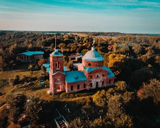 beige and teal church near forest during day