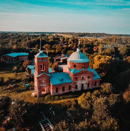 beige and teal church near forest during day