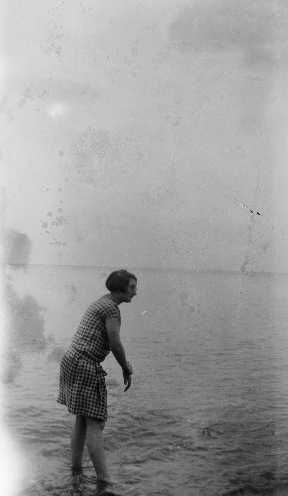 grayscale photography of woman standing near seashore