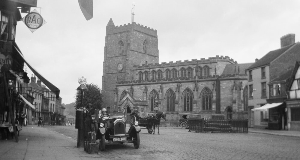 grayscale photography of people and vehicles near castle