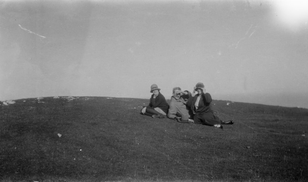grayscale photo of three people sitting on ground