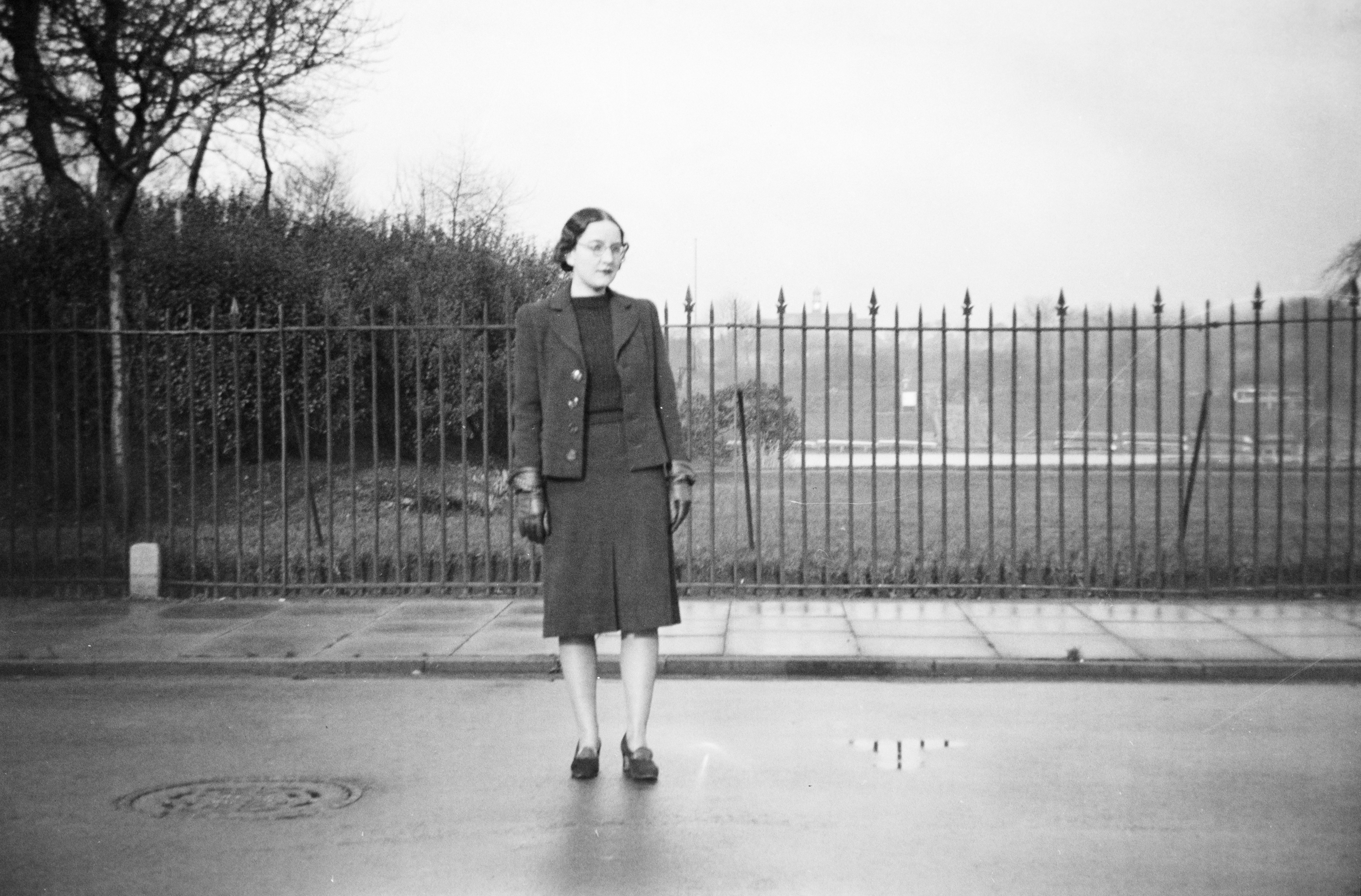grayscale photography of woman standing near road