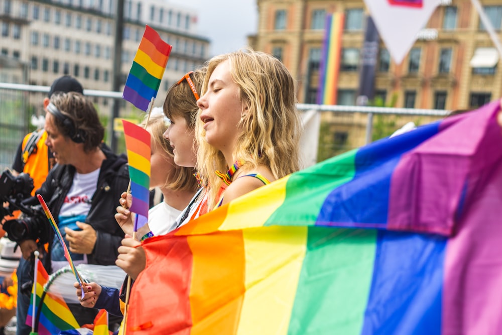 personnes tenant des drapeaux arc-en-ciel