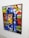 A vibrant, abstract painting featuring a mosaic pattern. A central prominent element is a single eye, partially visible behind colorful geometric shapes. The artwork combines a diverse mix of colors and symbols, including stars and swirl motifs.