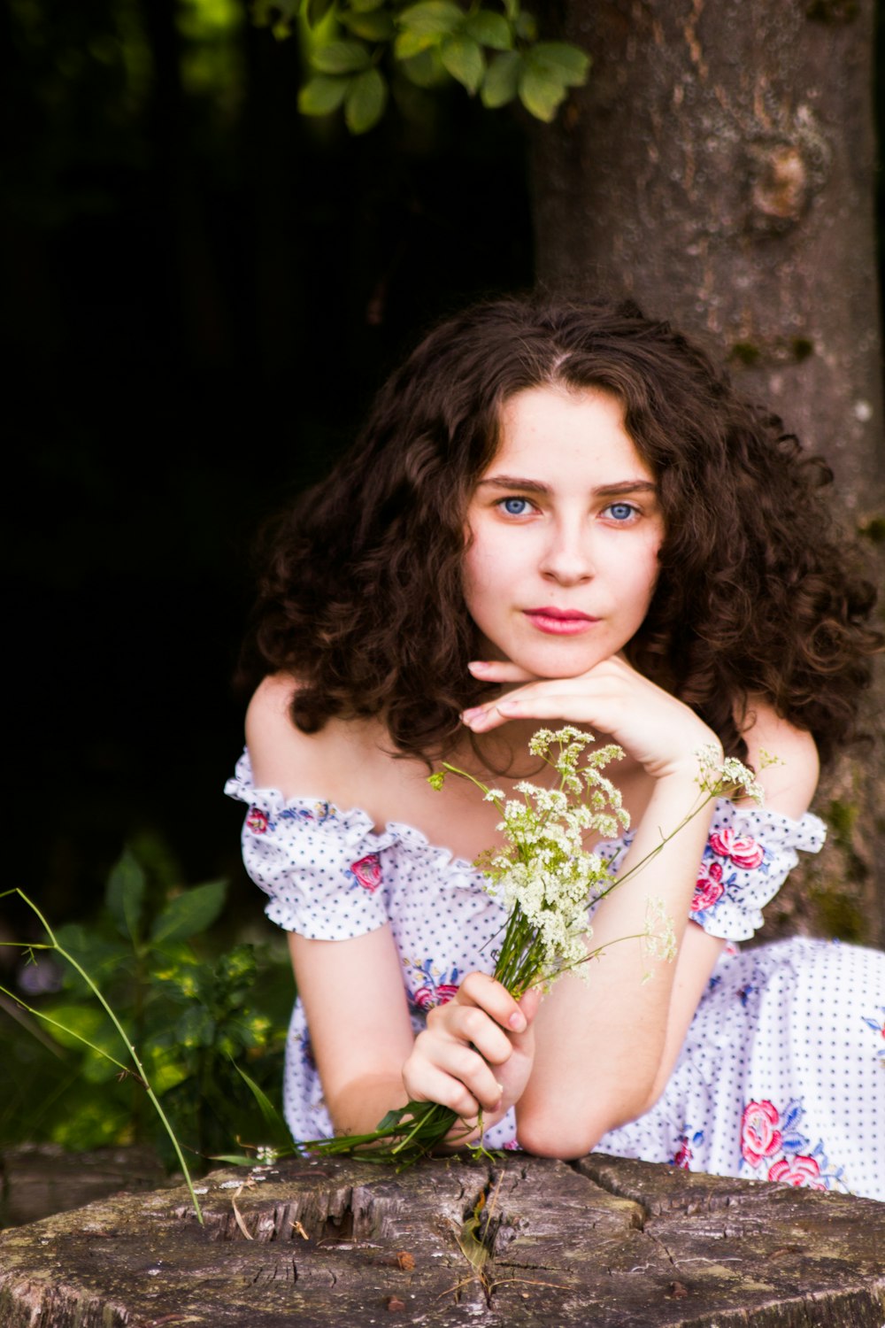 woman resting her head holding yellow-petaled flowers