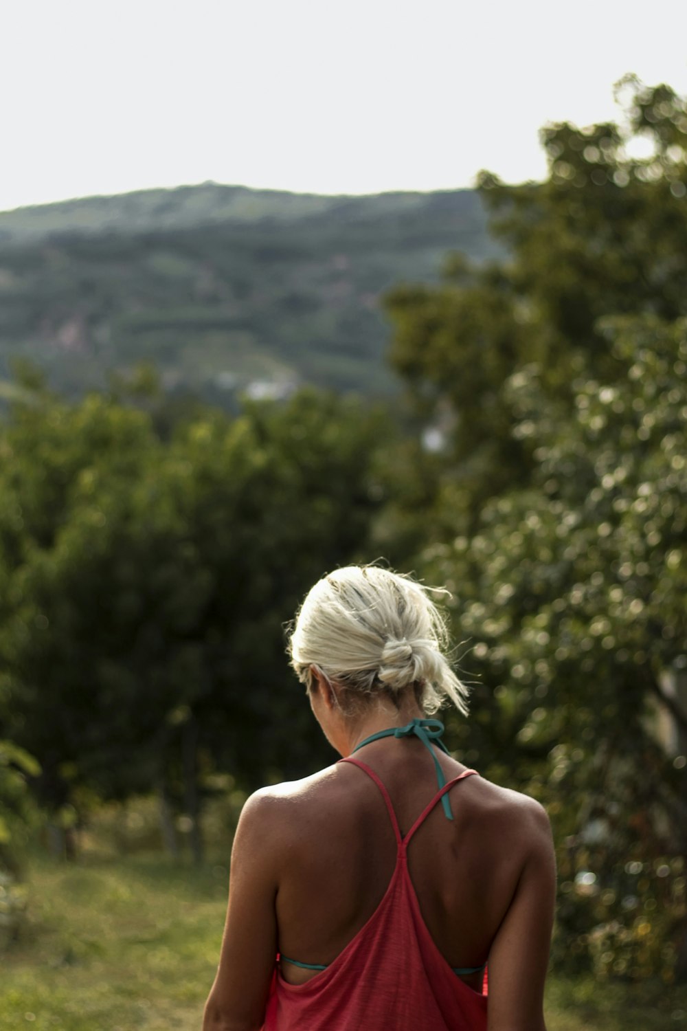 woman wearing pink tank top standing in front of green mountains