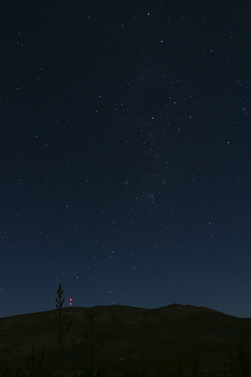 the night sky with stars above a hill