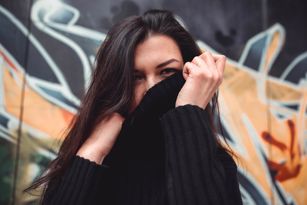 mujer cubriendo su rostro en suéter negro