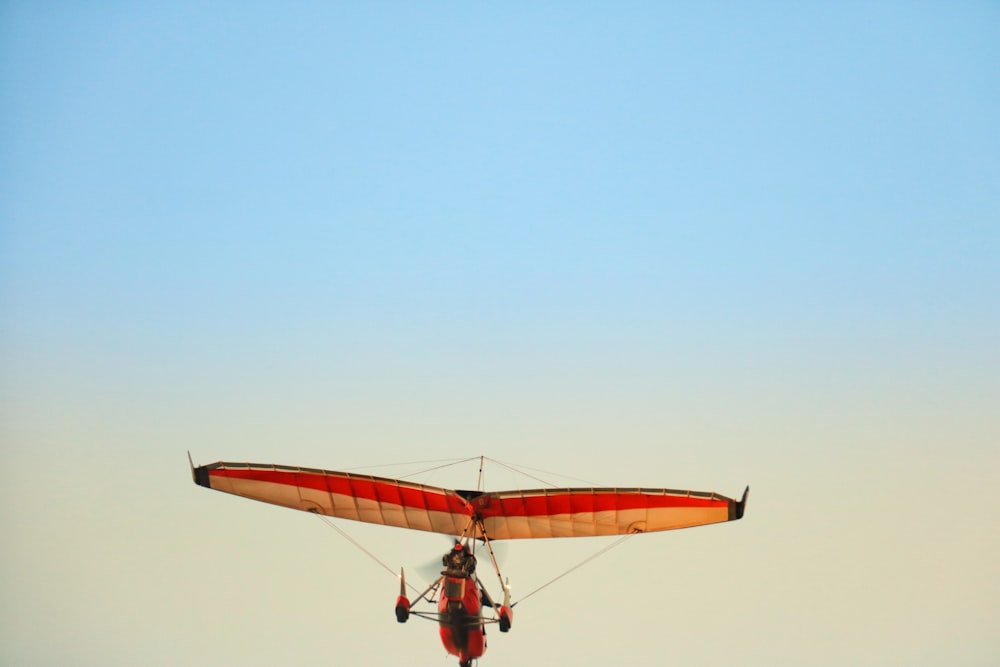 brown and red monoplane flying during daytime
