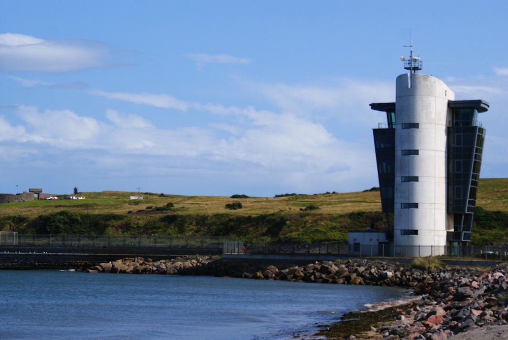 torre na costa rochosa e grama durante o dia