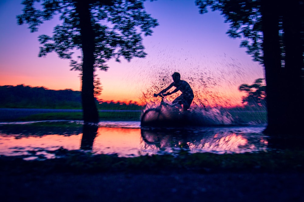 silhouette photo of man riding bicycle