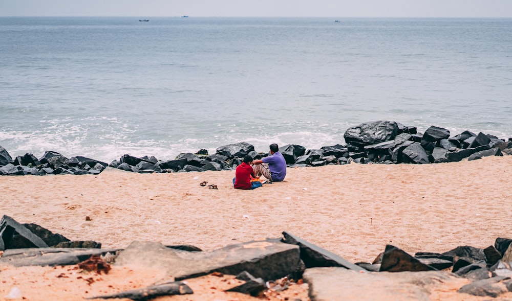 Foto de una persona con camisa roja y morada sentada en la orilla del mar