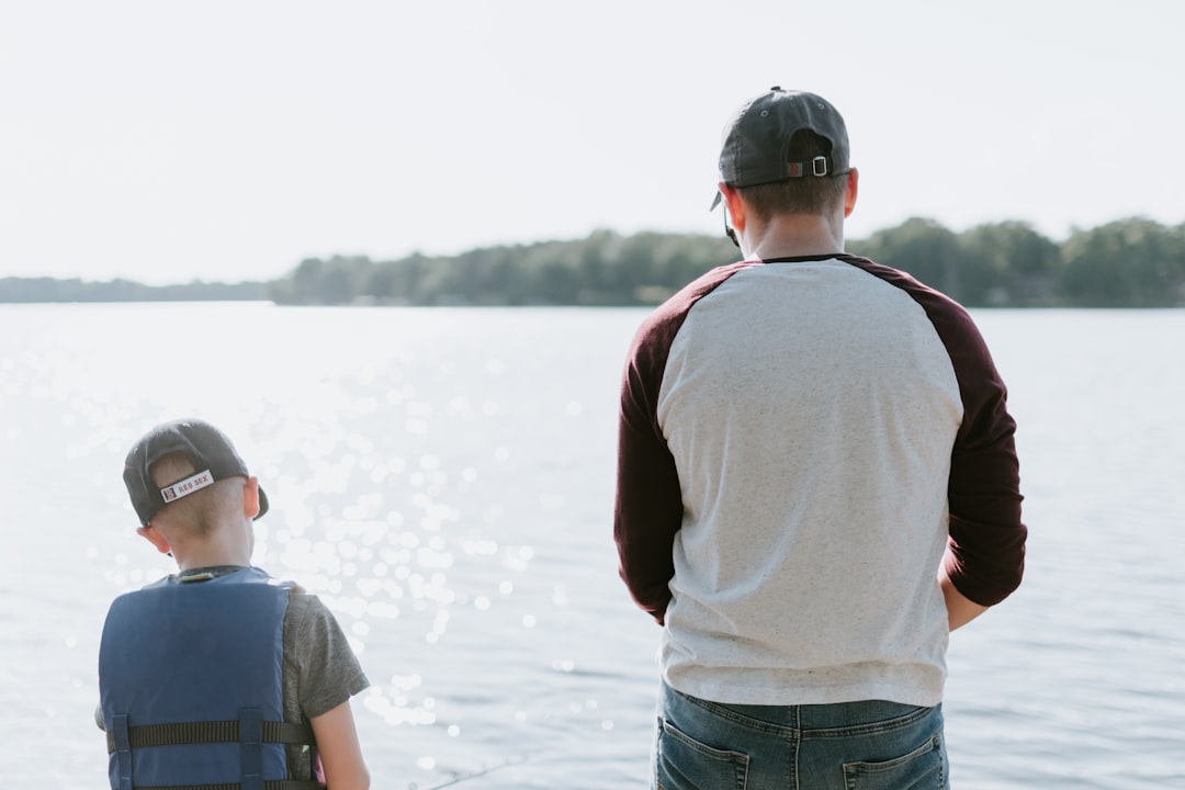 man and boy fishing on water, Father and son fishing, both with Red Sox hats on</p>
<p>