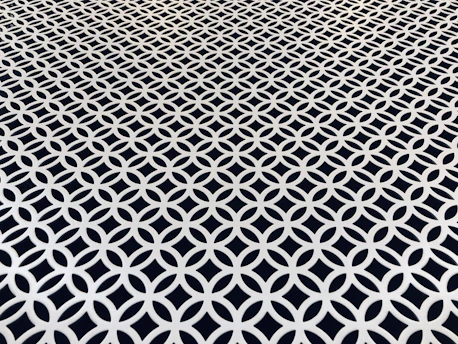 Square image of a hand-tufted rug with bold geometric patterns in black and white.