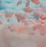 A whimsical scene depicting fluffy, cloud-like formations in pastel pinks and blues. The soft textures blend seamlessly, giving a dreamy and ethereal quality.