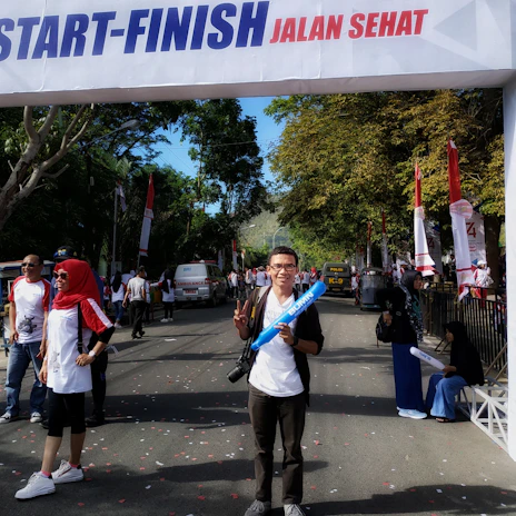A focused event manager coordinating a lively marathon with vibrant sponsor banners.