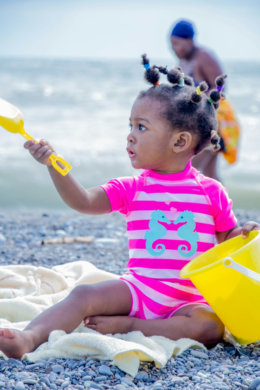 girl wearing white and pink shirt sitting on sand