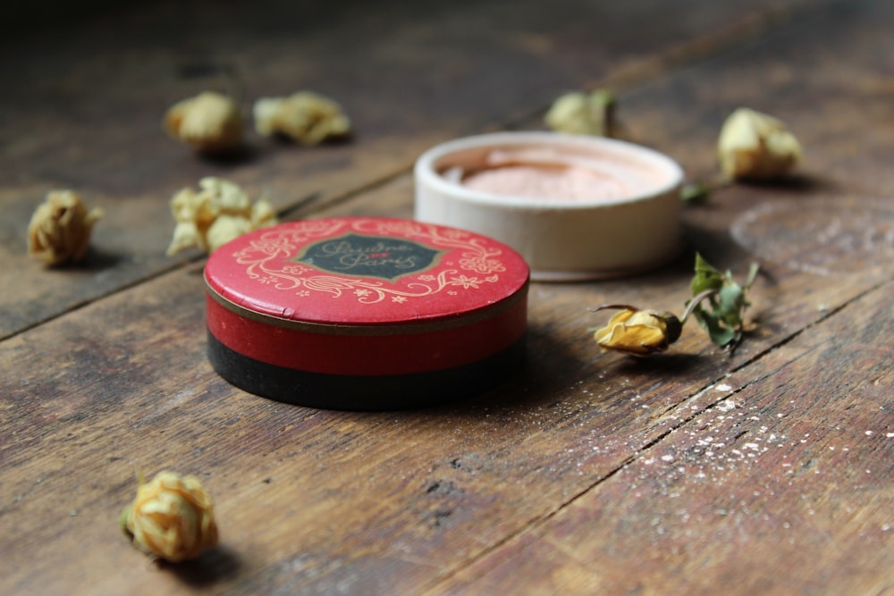 opened container beside yellow flowers on wooden surface