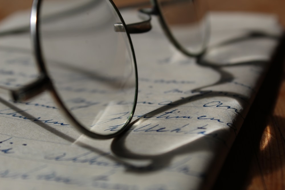 óculos de moldura prateada sobre papel com caligrafia