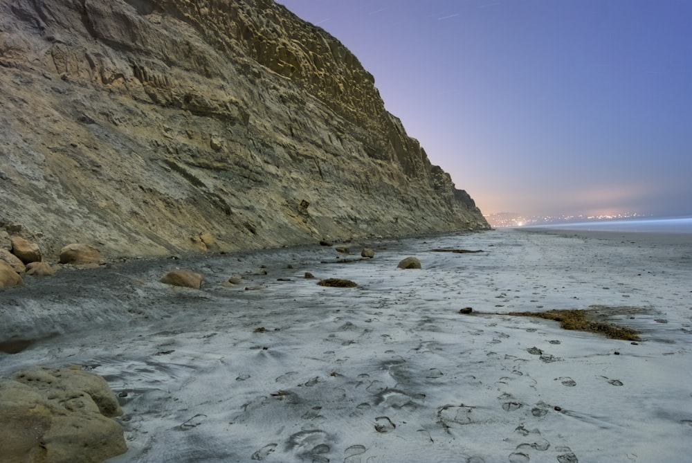 une plage de sable à côté d’une falaise rocheuse