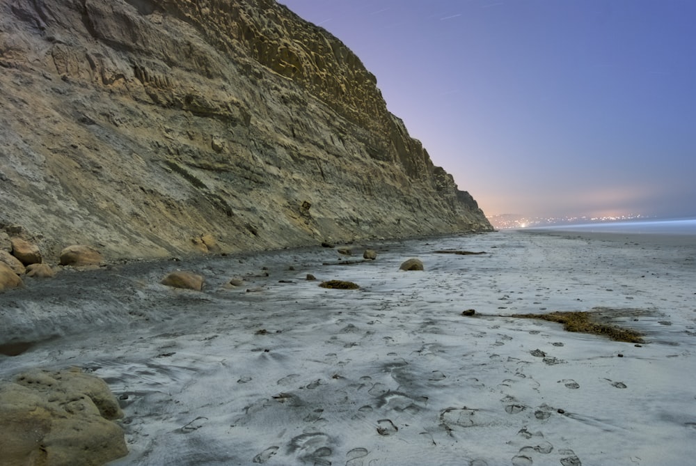 a sandy beach next to a rocky cliff