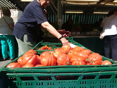 Close-up of a vendor selecting ripe tomatoes at a local market stall.