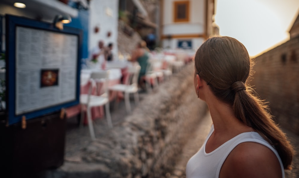 woman wearing white tank top glancing her right side