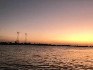 Sunset over a pristine lake with electrical poles blending into the natural landscape.