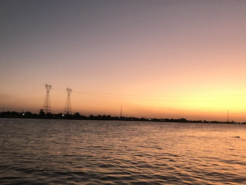 Sunset over a pristine lake with electrical poles blending into the natural landscape.