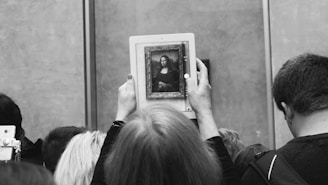 a black and white photo of a person holding up a picture