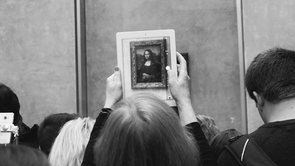 a black and white photo of a person holding up a picture
