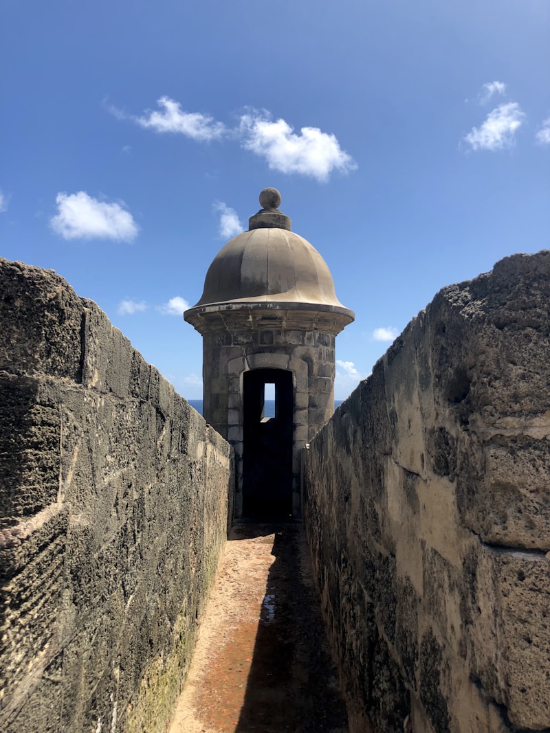 Domed stone sentry box framed by weathered fortress walls under a blue sky at El Morro