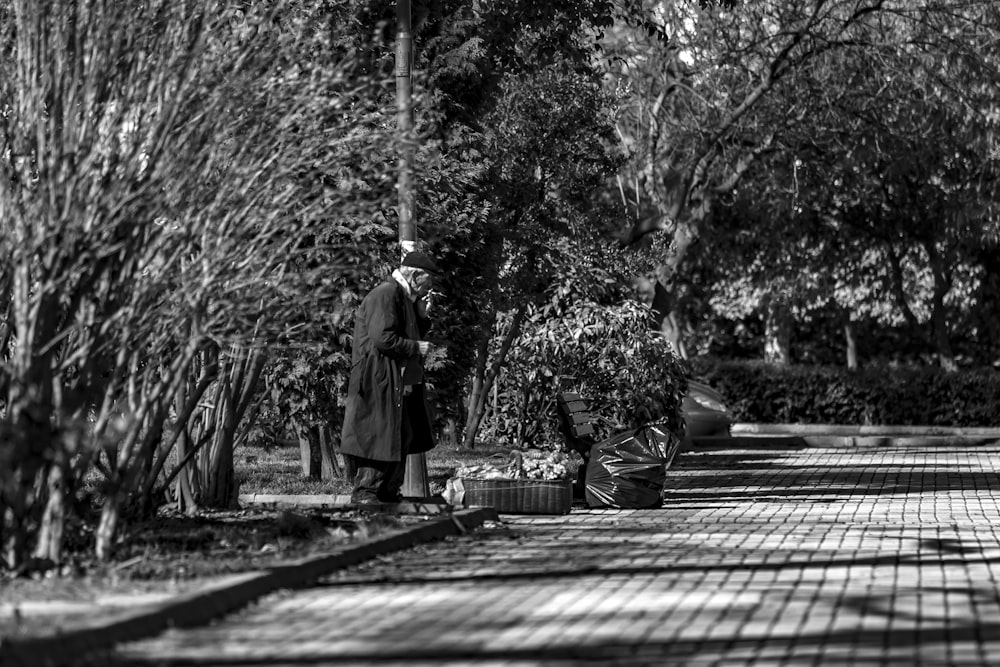 greyscale photography of man standing on curb during daytime