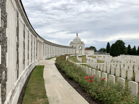 A serene memorial wall with names of fallen American service members etched in stone under a clear blue sky.