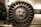 A large, round, metallic vault door with intricate spokes and a central locking mechanism dominates the image. The surroundings are industrial and metallic, featuring bolts and structured patterns.