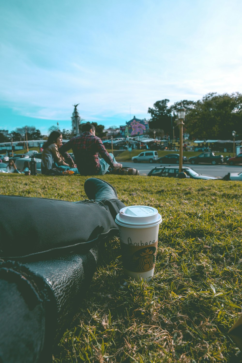 sitting person on grass beside white disposable cup