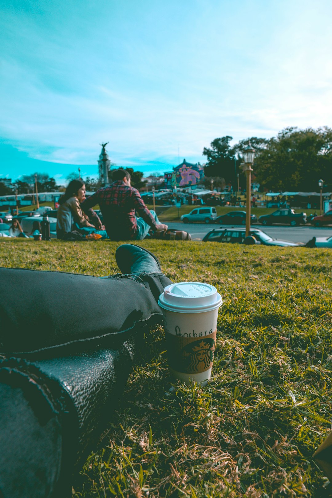 sitting person on grass beside white disposable cup