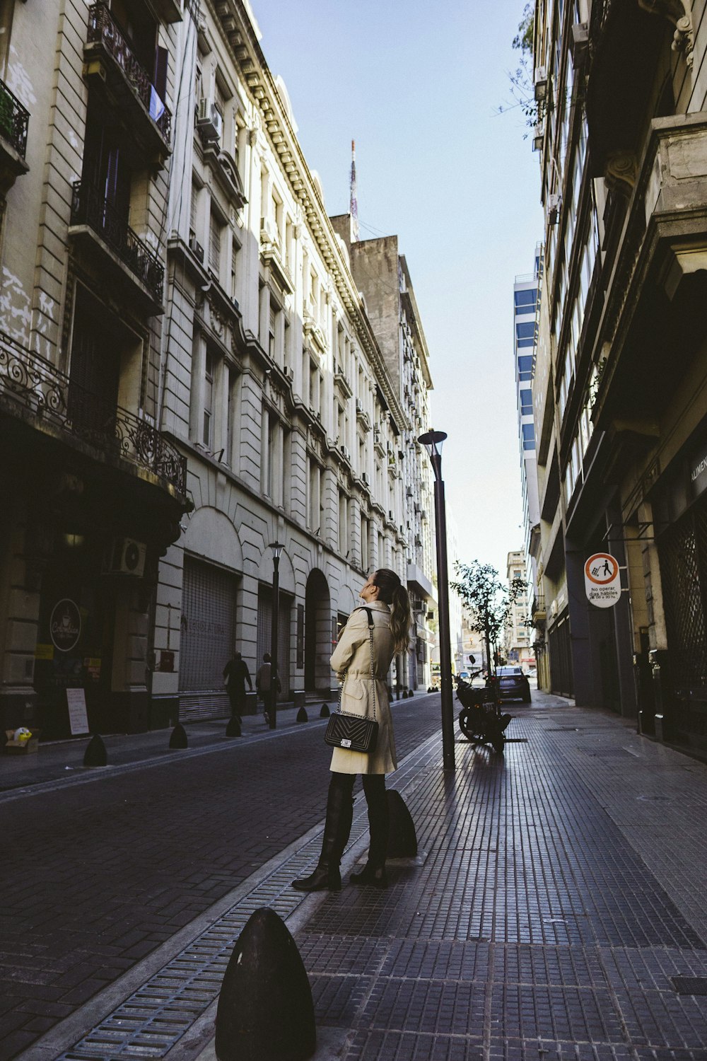 woman standing on sidewalk beside post