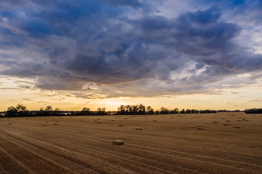 a field with bales of hay under a cloudy sky