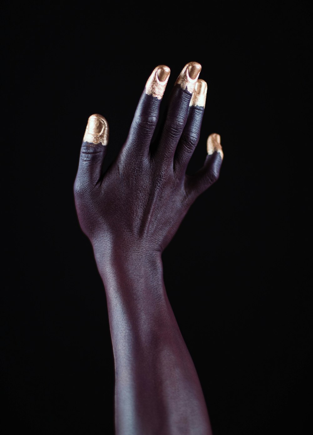 a woman's hand with gold nail polish on it