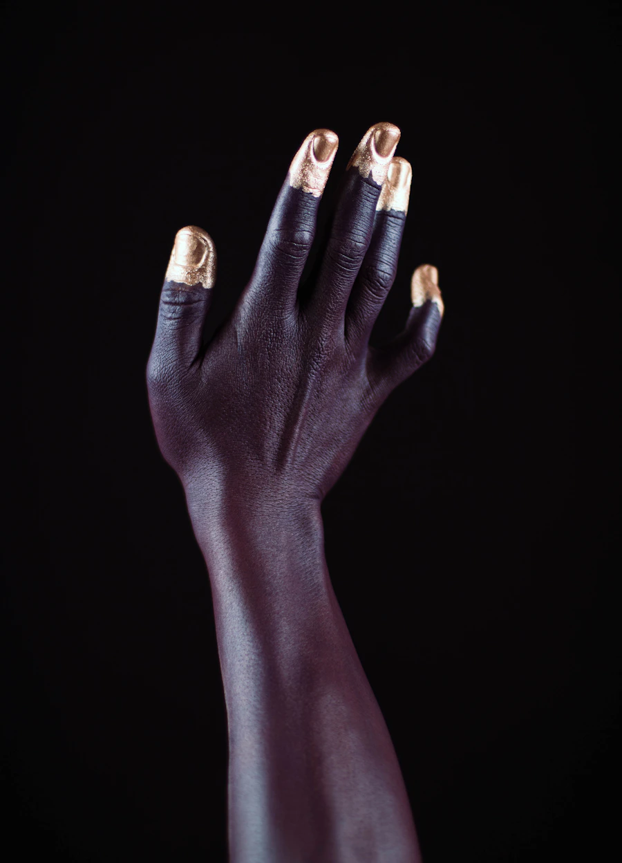 Dark-skinned hand with gold nail polish