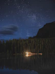 Night view of the cabins illuminated softly under a starry sky beside the flowing river.