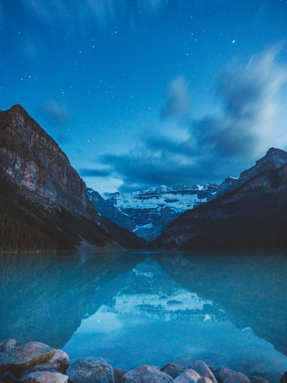 um lago cercado por montanhas sob um céu noturno