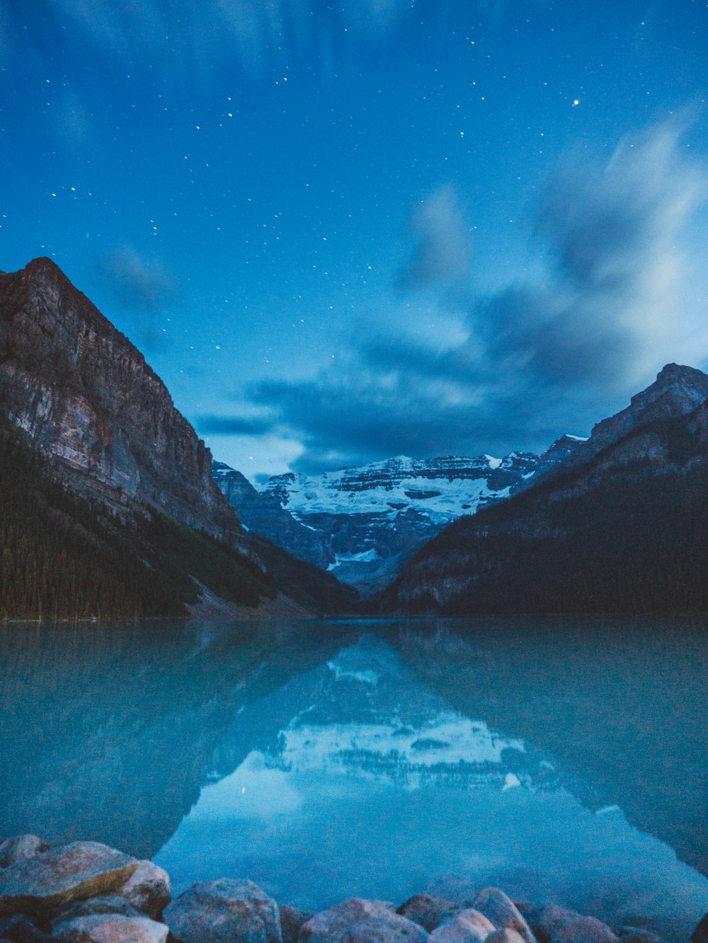 a lake surrounded by mountains under a night sky