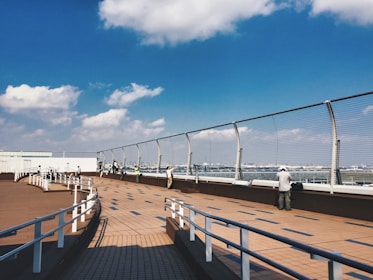 An outdoor networking event with aviation professionals under a clear sky near an airport runway.