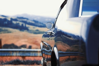 A sleek black car parked in a scenic location.