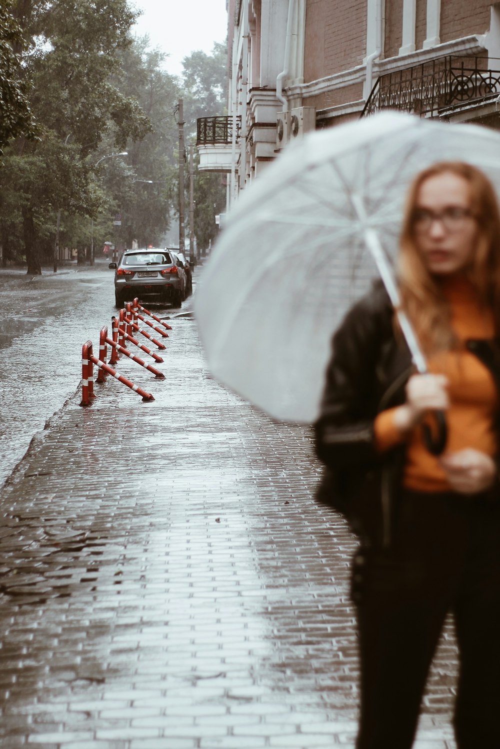 woman with umbrella standing on sidewalk near building